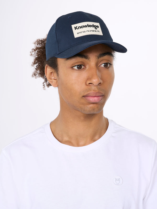 KnowledgeCotton Apparel - UNI Twill baseball cap with siliconebadge Caps 1001 Total Eclipse