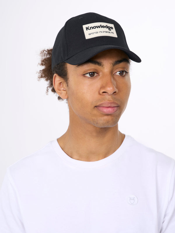 KnowledgeCotton Apparel - UNI Twill baseball cap with siliconebadge Caps 1300 Black Jet