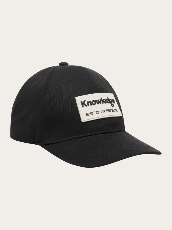 KnowledgeCotton Apparel - UNI Twill baseball cap with siliconebadge Caps 1300 Black Jet